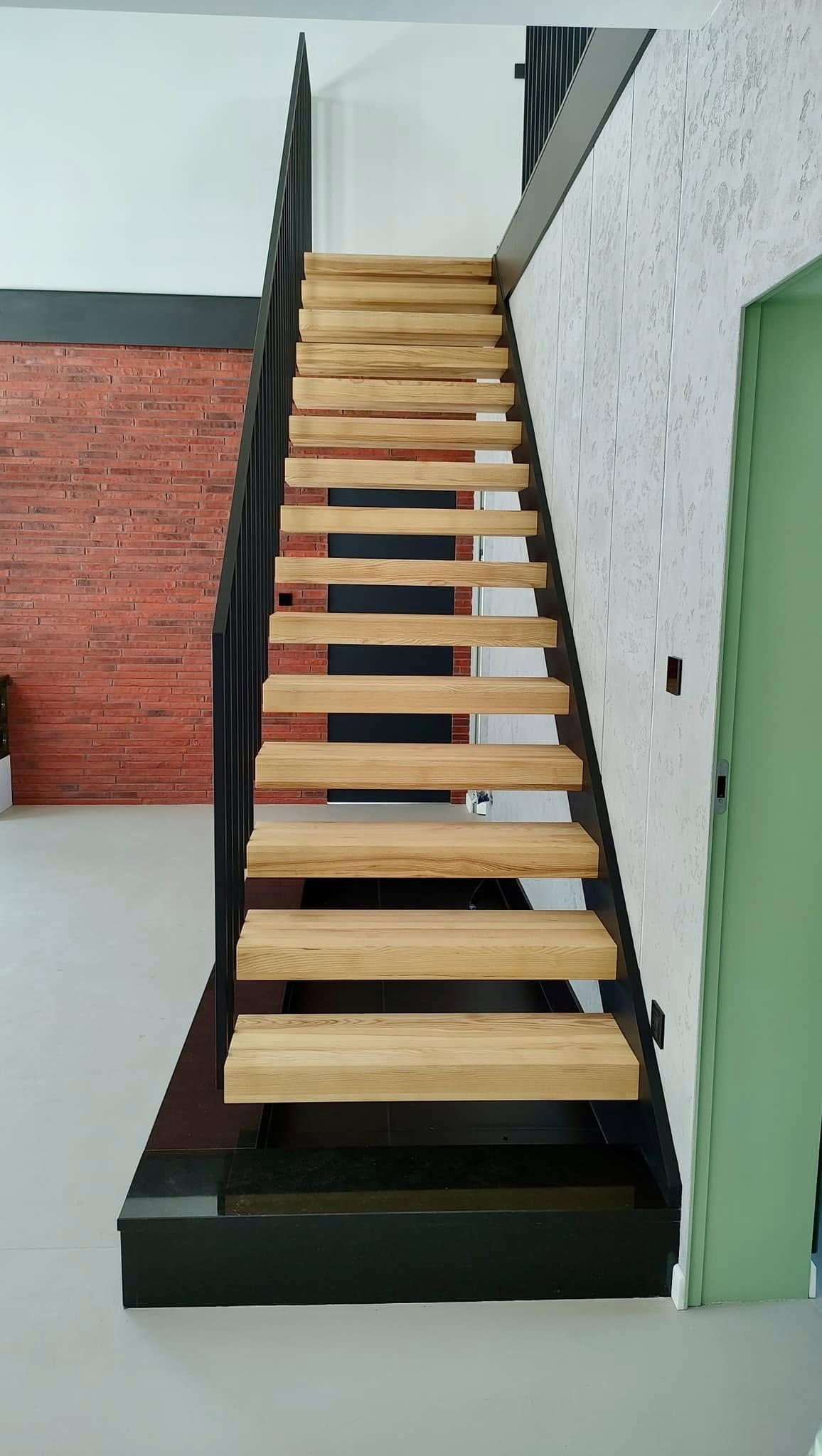 Schody samonośne z dębowymi stopniami na czarnej konstrukcji stalowej Ełk